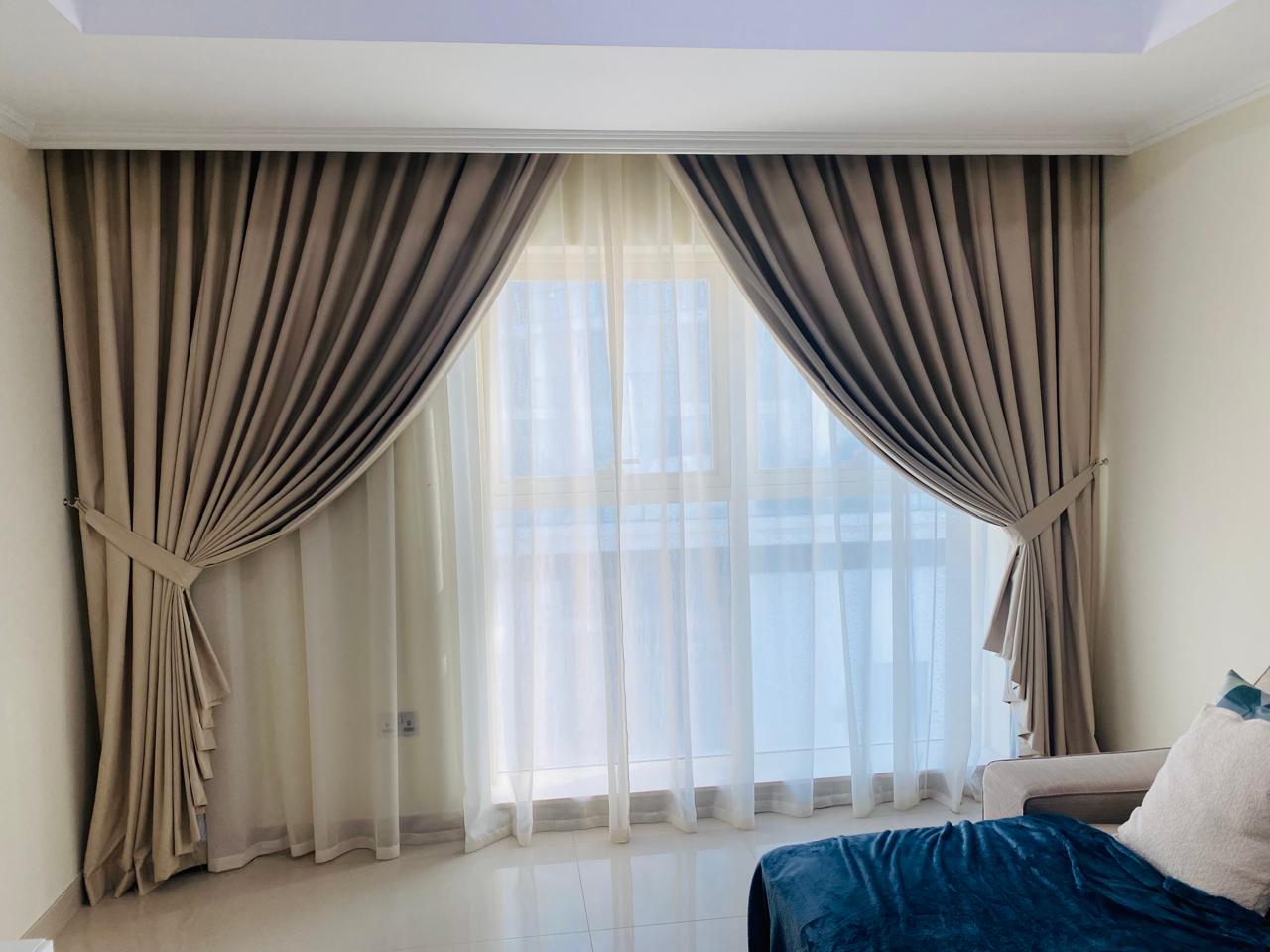 Pleated drapes with tie-backs layered over sheers in a bedroom