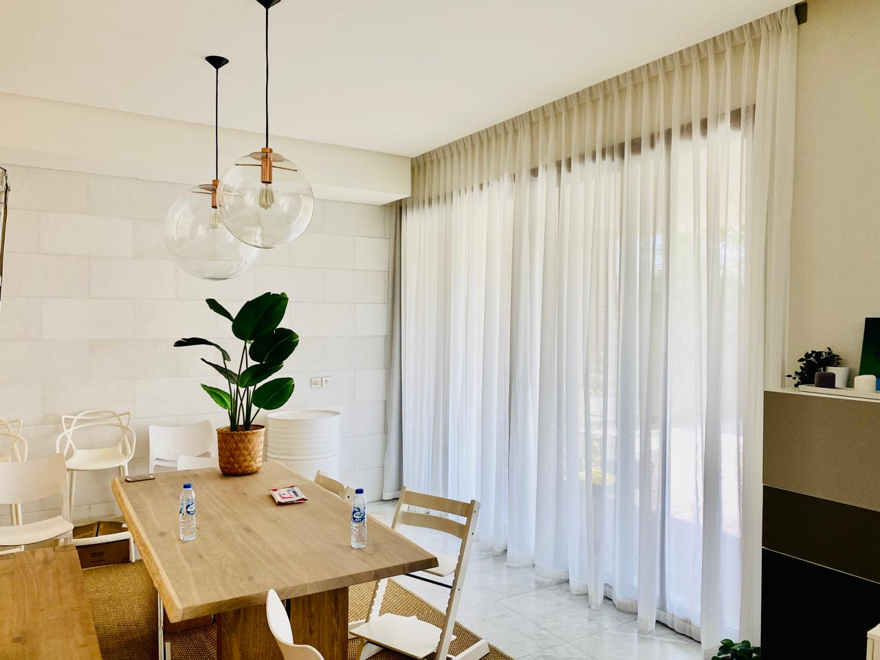 Sheer curtains filtering daylight across a bright dining room