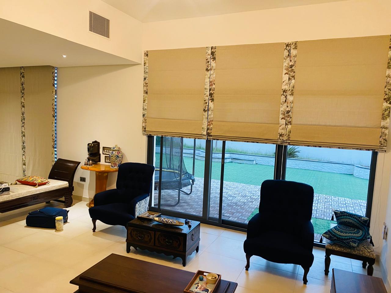 Linen Roman blinds with patterned borders fitted across a wide living room window